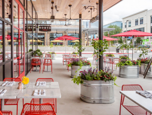 Red patio furniture and accompanying plants of West Legacy eatery, North Italia